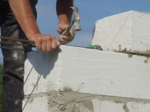 строитель укладывает блоки